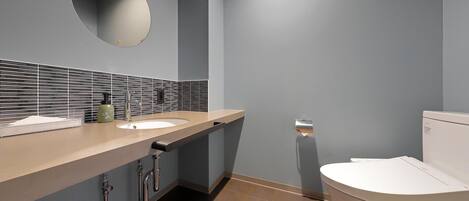 Un baño moderno con dos lavamanos, un inodoro y un espejo.