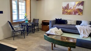 A room with a dining table, chairs, a sofa, and a painting on the wall. - Cajun Cabin Private Nature Resort (Minden Hills)
