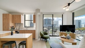 A modern apartment with a kitchen, dining area, and living room. It features a large window with a city view, a flat-screen TV, and a small balcony. - Crosby Miami WTC 2BR/2BA Urban Comfort #614 (Miami)