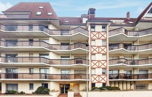 Ein mehrstöckiges Wohngebäude mit Balkonen, einem zentralen Eingang und einer markanten, geometrischen Fassade.