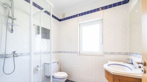 A bathroom with a glass shower enclosure, a toilet, a sink, and a window. - A spacious three-floor villa perfect for relaxing with friends or family. (Estoi)