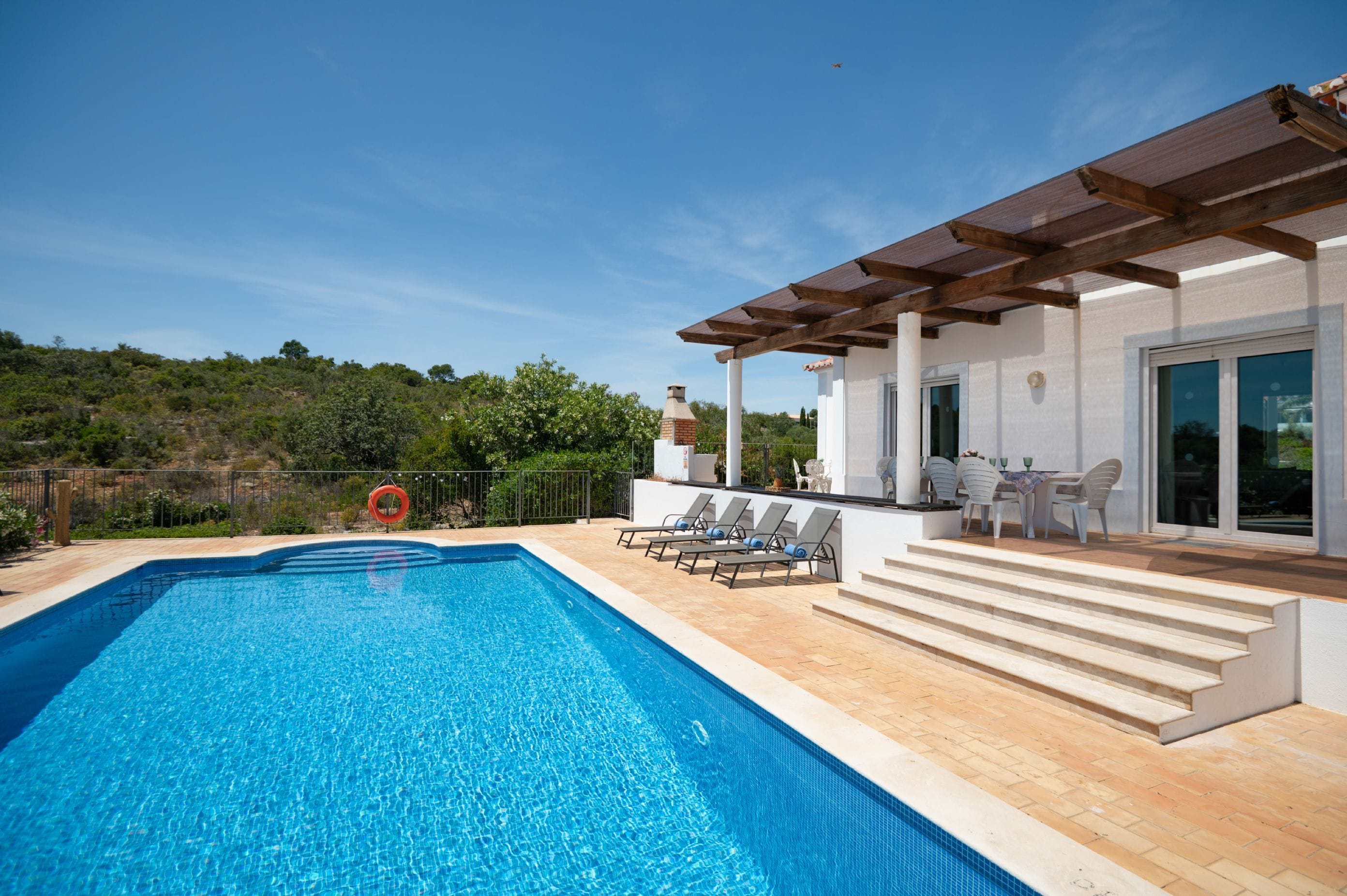 A swimming pool with lounge chairs and a covered patio area.