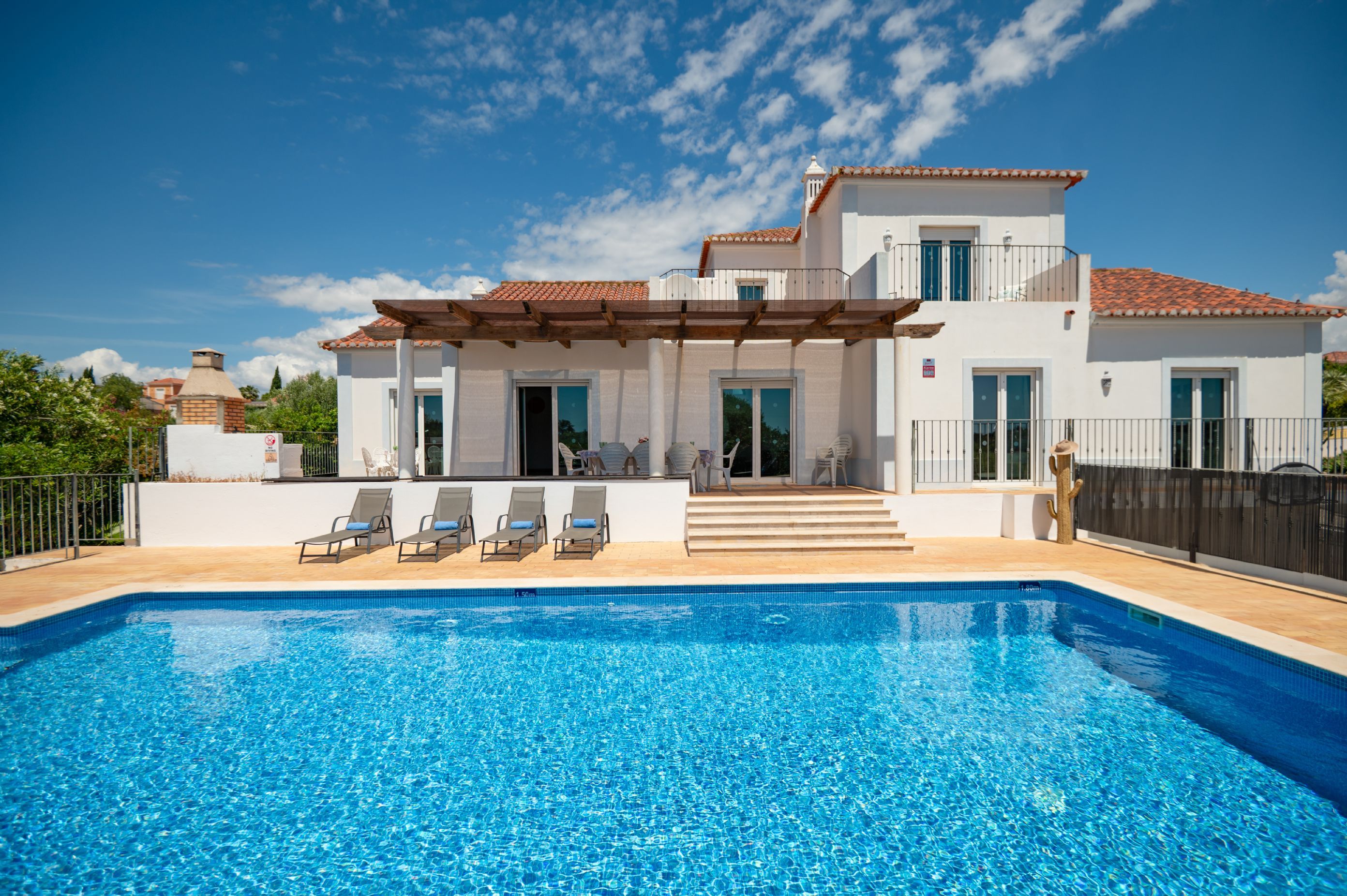 Eine moderne Villa mit Pool, Gartenmöbeln und einer überdachten Terrasse.