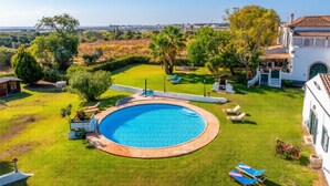 A pool surrounded by a well-maintained lawn, a white building with a tiled roof, and a clear view of the landscape. - A peaceful Fuseta escape with terrace, garden, and private parking. (Fuseta)