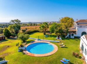 A pool surrounded by a well-maintained lawn, a white building with a tiled roof, and a clear view of the landscape. - A peaceful Fuseta escape with terrace, garden, and private parking. (Fuseta)