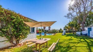 A patio with a table and benches, a pool, and a tree. - A peaceful Fuseta escape with terrace, garden, and private parking. (Fuseta)