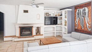 Ein modernes Wohnzimmer mit Kamin, weißen Möbeln, einem Flachbildfernseher und einem großen abstrakten Gemälde.