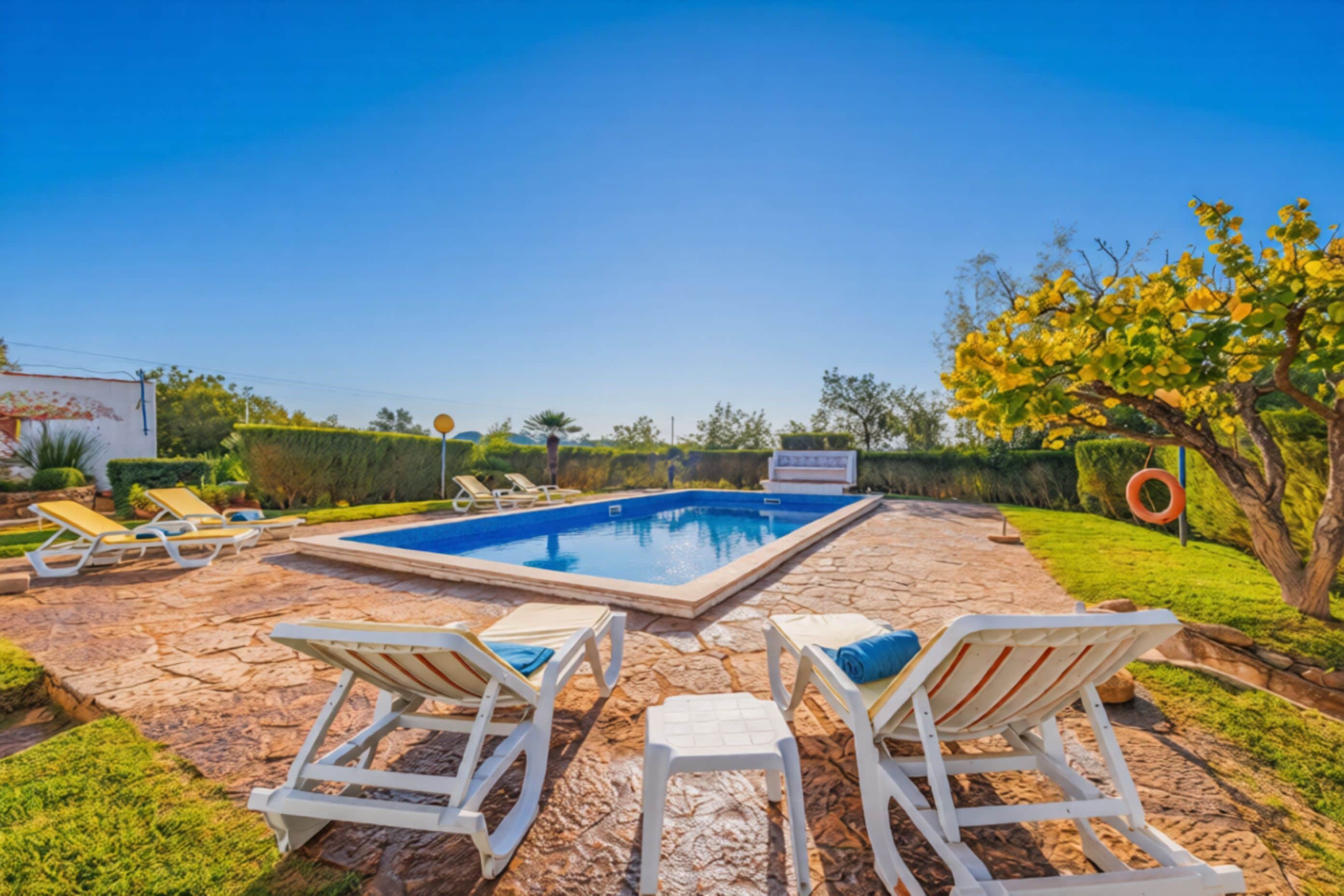 A swimming pool with lounge chairs and a stone patio.