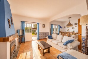 Un salon comprenant un canapé, une table basse, une cheminée et une vue sur l’extérieur.
