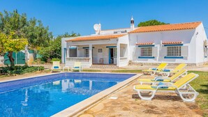 A poolside area with a swimming pool, lounge chairs, and a white building with a tiled roof. - Relax with sunrise, sunset, and countryside scenery from your private terrace. (Estoi)