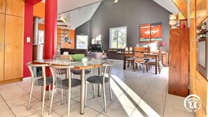 Una cocina amplia con electrodomésticos modernos, un comedor con una mesa grande y sillas, y una sala de estar con sofá y televisor.