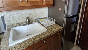 A kitchen with wooden cabinets, a granite countertop, a stainless steel refrigerator, and a white sink. - APARTMENT IN SANTA MARTA EL RODADERO LAURELES BUILDING 801 With ocean view (Gaira)