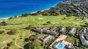 Luftaufnahme eines Golfplatzes mit Poolbereich, umgeben von Wohnhäusern und einem Strand.