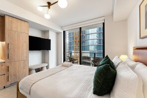 Ein modernes Schlafzimmer mit Bett, Fernseher, Holzschrank und Balkon mit Blick auf die Stadt.