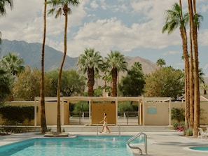 A pool area with palm trees, a person walking, and mountains in the background. - Historic 1BR 2BR Retreat w Outdoor Shower & Private Patio in Palm Springs (Palm Springs)
