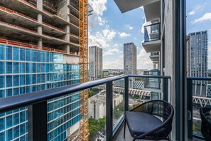 A balcony with a view of a cityscape, including high-rise buildings and a construction crane. - Crosby Miami WTC Studio Sleek #2506 (Miami)