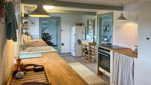 Ett kök med en bänkskiva i trä, en diskho, ett kylskåp och en matplats med ett bord och stolar.