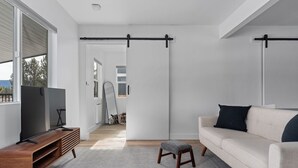 Un salon moderne avec un téléviseur posé sur un meuble en bois, un canapé beige et un tapis gris.