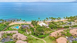 Eine Luftaufnahme eines Resorts mit mehreren Gebäuden, einem Schwimmbad und einem Strand.