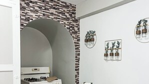 Een compacte keuken met een witte kookplaat, een klein tafeltje met geweven placematen en een spoelbak.