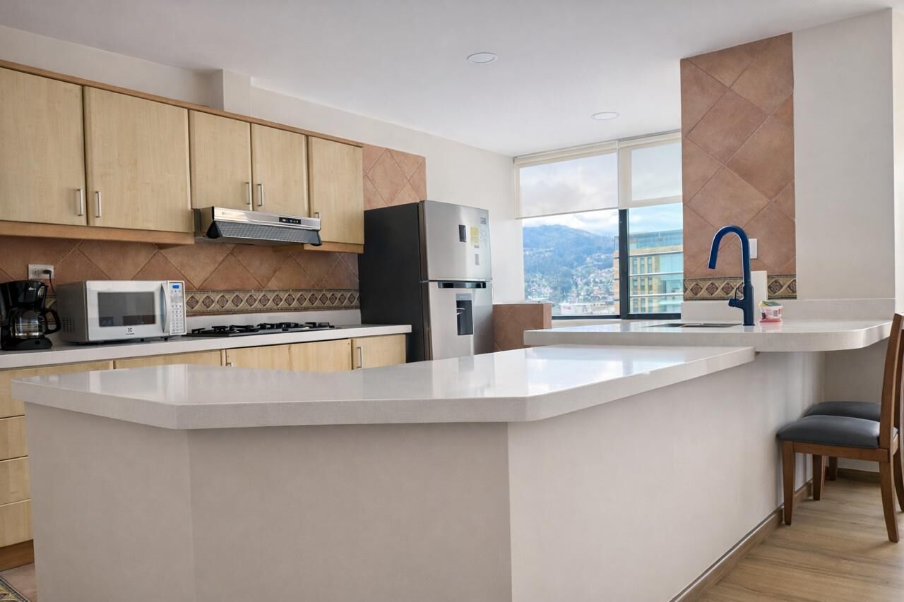 A modern kitchen with wooden cabinets, a built-in microwave, a gas stove, a refrigerator, and a large window offering a city view.