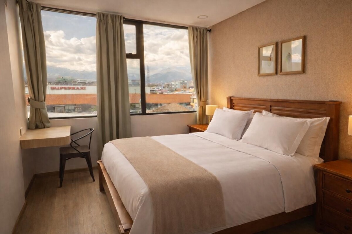 Una habitación de hotel con una cama, un escritorio y una silla.