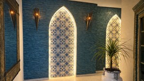 Un pasillo con paredes estampadas, iluminación decorativa y una planta en maceta.