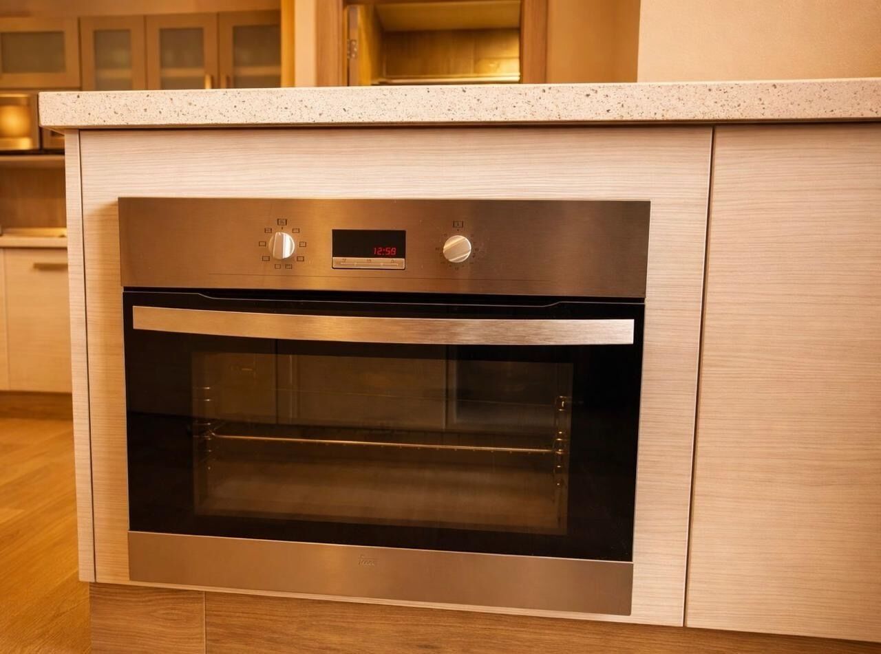 Una cocina moderna con horno empotrado, un reloj digital y acabados de acero inoxidable.
