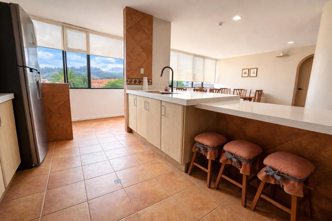 A kitchen with a large island, a refrigerator, and a view of the outdoors.