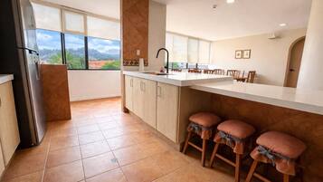 A kitchen with a large island, a refrigerator, and a view of the outdoors.