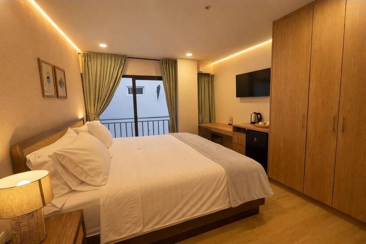 A hotel room with a bed, a desk, a television, and a wardrobe.