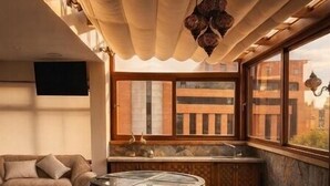Un interior moderno con sofá, una mesa redonda y una zona de cocina con ventana.