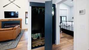 Un salon moderne avec une cheminée, un canapé et un téléviseur fixé au mur.