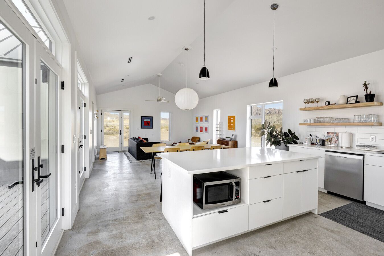 A modern kitchen with white cabinetry, a central island, and pendant lighting.
