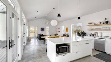 A modern kitchen with white cabinetry, a central island, and pendant lighting.