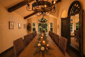 A dining area with a long wooden table, wicker chairs, candles, and a chandelier. - Red Rock Views • Pool, Spa, Sauna, Cinema & Fitness • Luxe 5BR Sedona Retreat (Sedona)