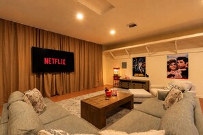 Una sala de estar con una televisión de pantalla plana, una mesa de centro y dos sofás.