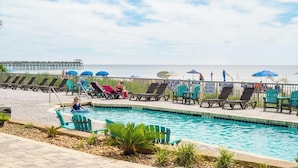 A pool area with lounge chairs and umbrellas, a pier in the background, and a clear view of the ocean. - Experience the Ultimate Beachfront Lifestyle at Ocean's One (Myrtle Beach)