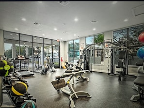 A gym with various exercise equipment, large windows, and a view of trees outside. - Spacious 5-bedroom house in beautiful Loughman with AC and gym (Loughman)