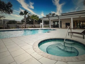 A swimming pool with lounge chairs and a hot tub, surrounded by a patio area with a building in the background. - Spacious 5-bedroom house in beautiful Loughman with AC and gym (Loughman)