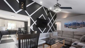 Una sala de estar moderna con comedor, un sofá y un televisor montado en la pared.