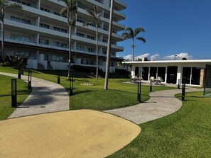 Un hotel moderno con un patio central, palmeras y una zona de estar cubierta.