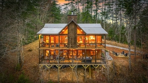 A two-story log cabin with a deck, surrounded by forest. - 249 Ranger Station - Mountain View | Pet Friendly | Hot Tub | Shuffleboard | Cornhole (Morganton)