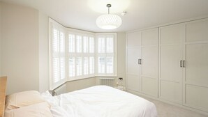 A bedroom with a bed, a radiator, a window with blinds, and a wardrobe. - 2BR Garden Flat Near Richmond and Stadium (Twickenham)