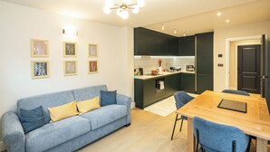 A modern apartment with a grey sofa, a wooden dining table, and a kitchen with dark cabinets. - 2BR Garden Flat Near Richmond and Stadium (Twickenham)