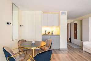 A compact hotel room with a dining area, kitchenette, and a bed. - Royal Tulip Sand Seaside Studio (Kołobrzeg)
