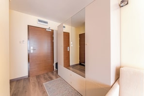 A hallway with a wooden door, a mirrored wardrobe, and a radiator. - Royal Tulip Sand Seaside Studio (Kołobrzeg)