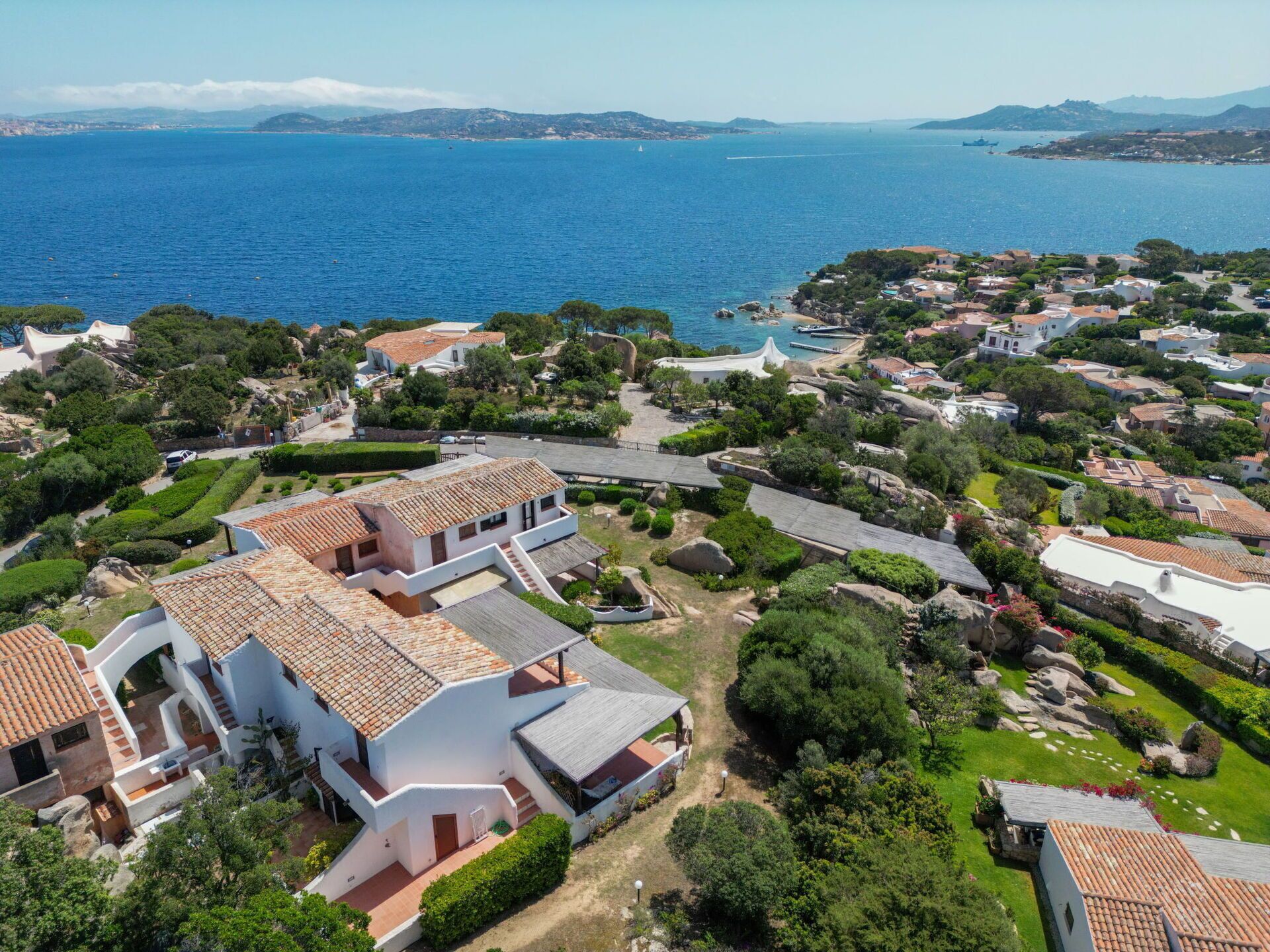 An aerial view of a coastal residential area with terraced houses, a marina, and a clear view of the sea.