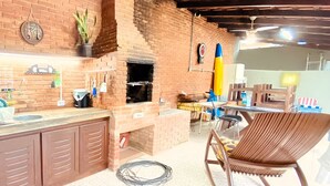 Une cuisine avec un mur en briques, un barbecue intégré et un coin repas comprenant une table et des chaises.