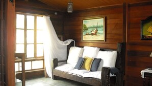 L’intérieur d’un chalet en bois, avec un lit, un tableau représentant un bateau sur l’eau et une décoration rustique.